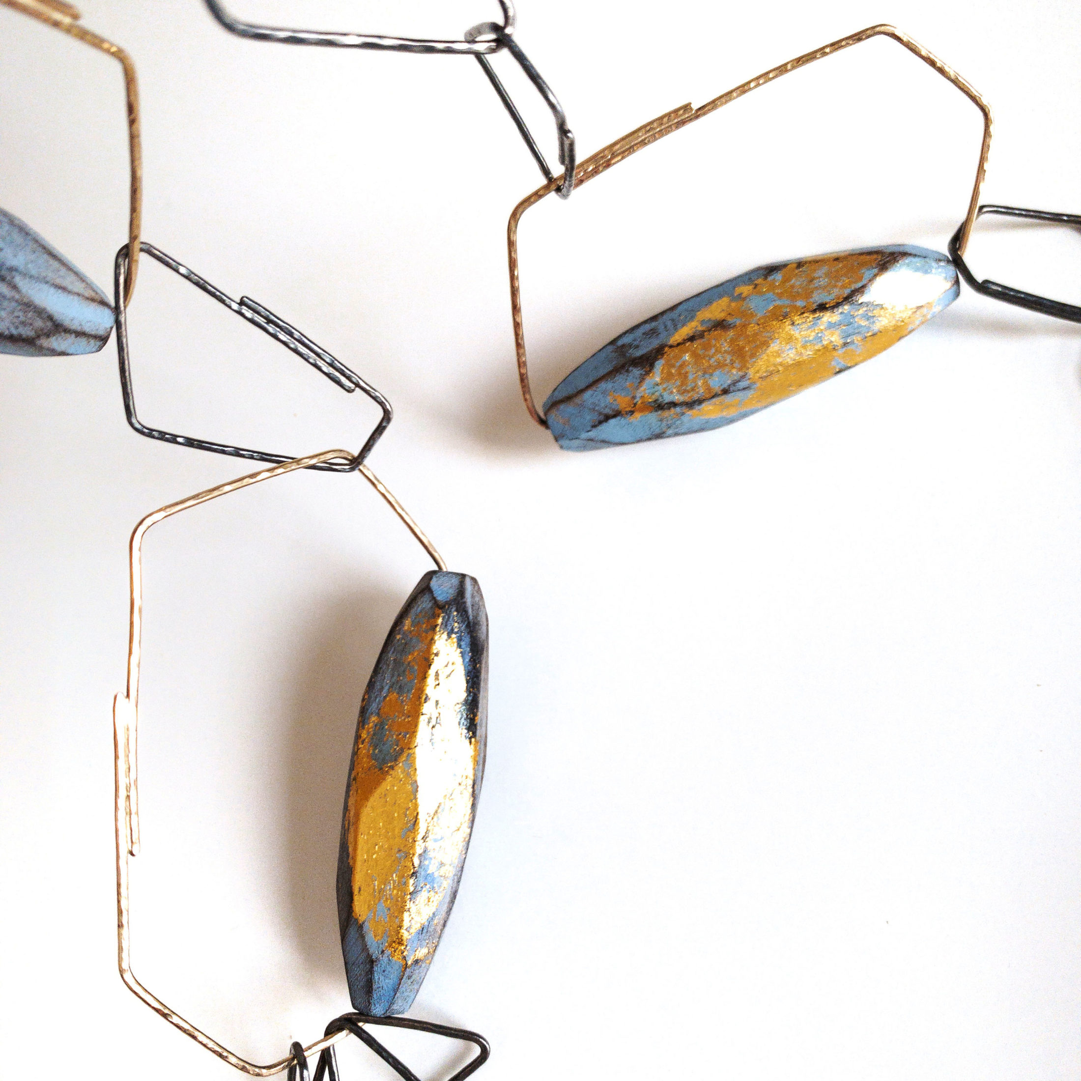 Blue and yellow wooden necklace on geometric pieces of precious metal.