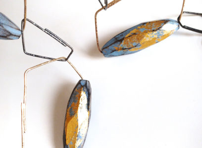 Blue and yellow wooden necklace on geometric pieces of precious metal.